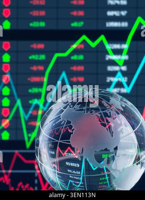 Transparent globe with stock market charts and data in the background. Stock Photo