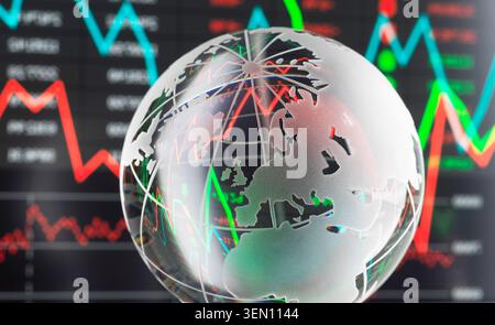 Transparent globe with stock market graphs and data on a screen in the background. Stock Photo