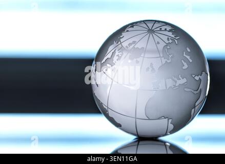Glass globe with continents etched in white on a reflective surface. Stock Photo