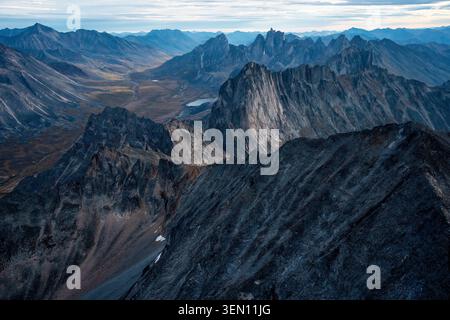 Rugged mountain range under a cloudy sky with sharp peaks and a distant valley. Stock Photo