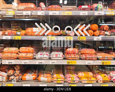 Kirov, Russia - January 14, 2026: Customers look at different types of sausage on shelves in a grocery store aisle while deciding what to buy for meal Stock Photo
