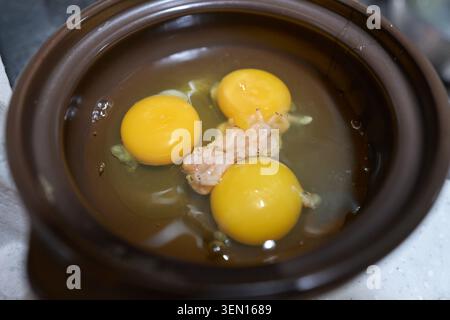 Raw yolks and fermented salted shrimp in a brown earthenware bowl, showcasing the authentic preparation of a traditional Asian steamed side dish. Stock Photo