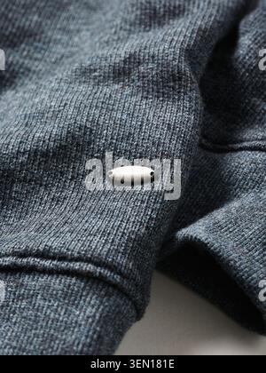 Close-up of a textured gray fabric with a small metallic button accent. Stock Photo