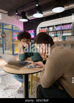 Two Coworkers Collaborating Over Laptop And Phone In A Casual Coworking Space Meeting Stock Photo