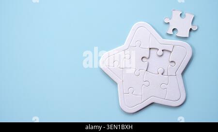 A white star-shaped jigsaw puzzle with one piece missing, set against a soft light blue background. Stock Photo