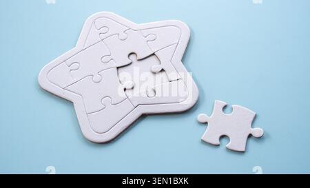 A close-up view of a star-shaped jigsaw puzzle with one piece separated, illustrating a concept of missing components. Stock Photo