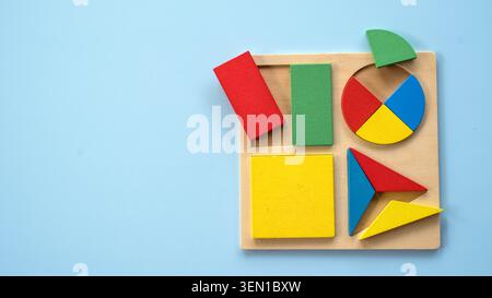 A wooden shape puzzle board featuring colorful geometric pieces like circles, triangles, and rectangles. Stock Photo