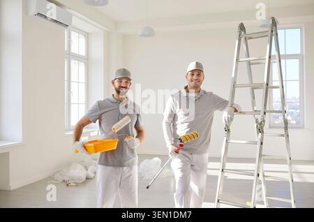 Team of house painters looking at camera holding paint rollers and going to paint the wall Stock Photo