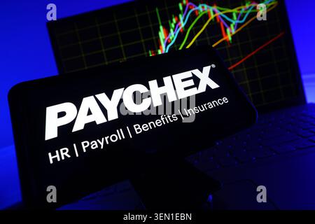 Paychex Payroll And HR Software Company Logo On Mobile Phone Screen With Stock Market Chart Stock Photo