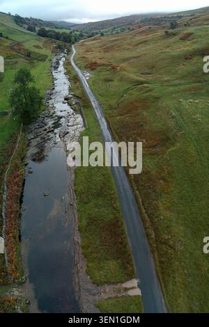 Aerial view of River Wharfe running parallel to a dale road in Langstrothdale with autumn hillsides beyond Stock Photo