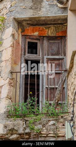 Old wooden window with peeling paint, iron railing and plants on a traditional stone building in Bocairent, Spain Stock Photo