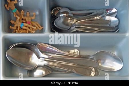 Male figures as drink markers in cutlery drawer with spoons Stock Photo