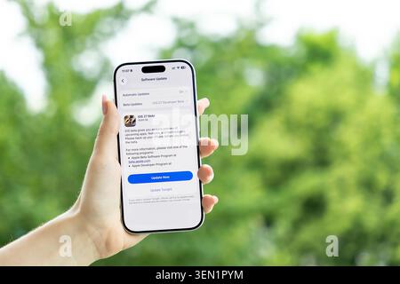 Poznan, Poland - June 9, 2026: Person holding a mobile device showing the iOS 27 software update interface, highlighting modern technology progress an Stock Photo