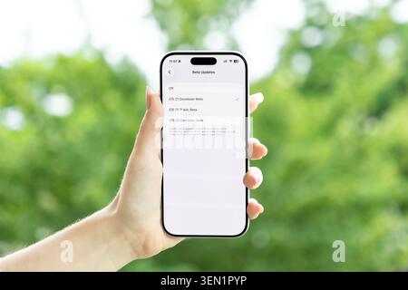 Poznan, Poland - June 9, 2026: Close up of a hand holding a mobile phone showing an iOS 27 beta selection screen, symbolizing current operating system Stock Photo