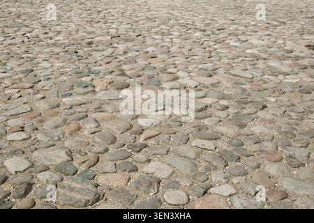Abstract background of an old cobblestone pavement. Stone pavement texture on the old town square. Stock Photo
