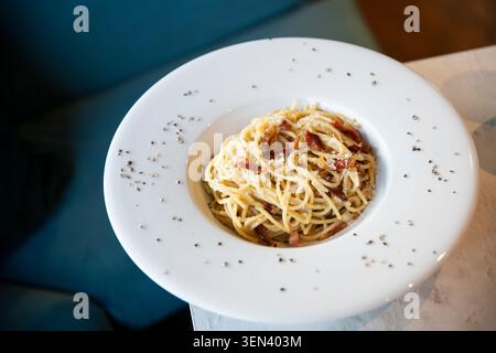 Delicious Spaghetti Dish Topped With Pepper and Herbs on a Marble Table Stock Photo