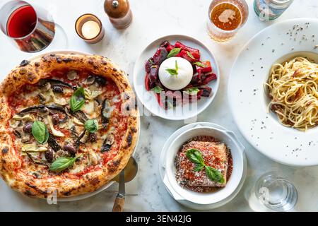 Delicious Italian Feast Featuring Pizza, Pasta, and Fresh Salad at a Trendy Dining Spot Stock Photo