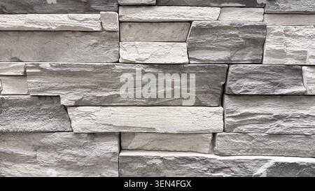 Gray stone wall texture in close-up with layered masonry pattern and rough surface. Stock Photo