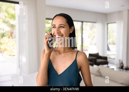 Young woman talking on smartphone at home Stock Photo
