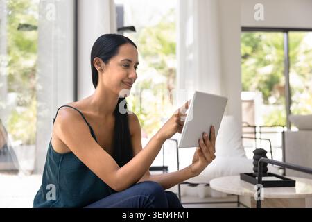Woman using digital tablet in modern living room Stock Photo