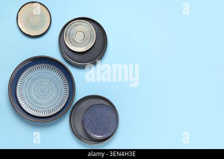 Ceramic dinnerware set with blue and gray plates, bowls, and saucers on a light blue background Stock Photo