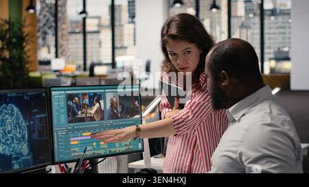 Creative team editing film footage with artificial intelligence software, transforming raw recorded clips into montage. Dual monitors show optimization tools powered by machine learning. Stock Photo