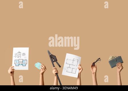Hands holding architectural blueprints, drafting tools, eyeglasses, and wallet with money on brown background Stock Photo