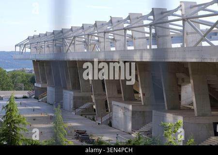 Modern concrete stadium featuring brutalist architecture. Showcasing a large seating tiers structure under construction with a prominent roof. Designe Stock Photo