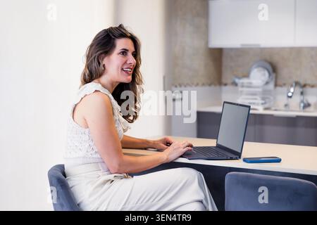 Woman working remotely from home with laptop Stock Photo