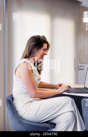 Woman smiling while working on laptop in home office Stock Photo