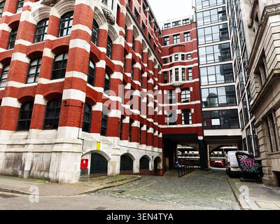 Manchester, UK - May 07, 2026: Historic red brick building and narrow cobbled alley in urban Manchester UK with architectural contrast. Stock Photo