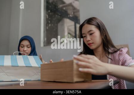 Two women unpacking cardboard boxes during a home move in a bright modern room Stock Photo