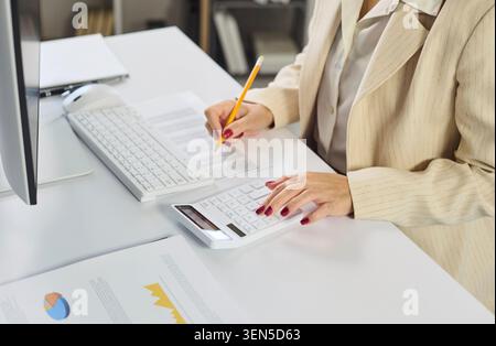 Female accountant using calculator and keyboard for budgeting and finance in office Stock Photo
