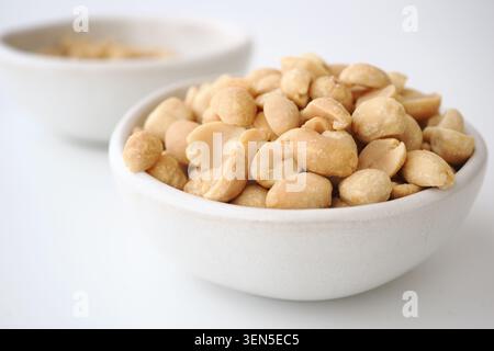 Bowl filled with shelled peanuts on a white background Stock Photo