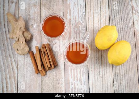 Brewing ginger tea with lemon and cinnamon on wooden table Stock Photo