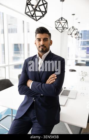 Confident businessman in suit posing in boardroom with arms crossed Stock Photo