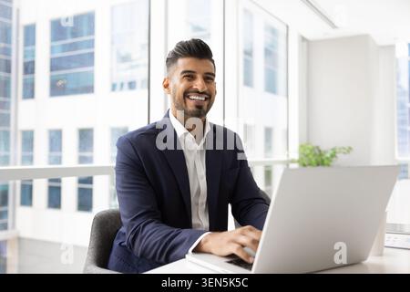 Business man sitting at desk with laptop in modern office Stock Photo