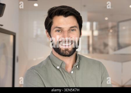 Headshot portrait of confident bearded man smiling at camera Stock Photo