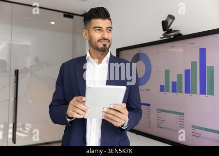 Thoughtful businessman working on tablet, making strategic decisions in office Stock Photo