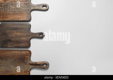 Three dark wooden cutting boards with handles on white background, kitchen utensils and food preparation, these kitchen utensils provide a rustic surf Stock Photo