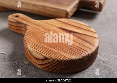 Round wooden cutting board with handle on gray concrete surface, kitchen utensil and food preparation tool, the kitchen utensil features natural wood Stock Photo
