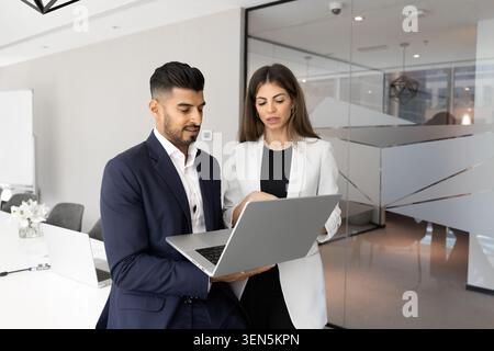Colleagues using laptop analyzing data together in office Stock Photo