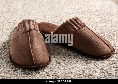 Comfortable brown house slippers on soft carpet, cozy home footwear for relaxation and indoor comfort Stock Photo