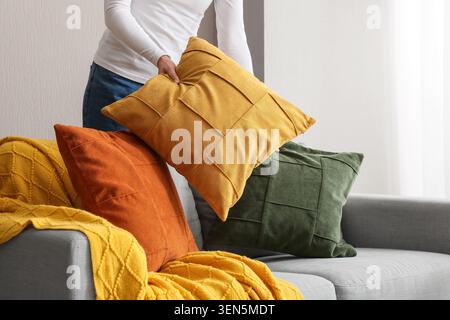 Woman arranging decorative pillows on a modern sofa, home decor and interior design concept, cozy living space Stock Photo