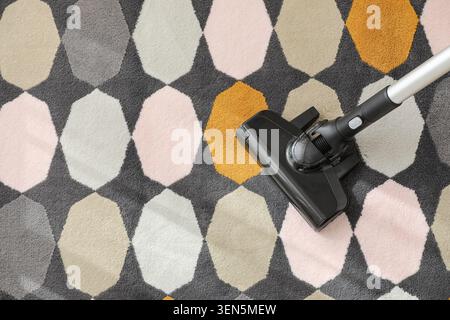 Vacuum cleaner head cleaning modern geometric patterned carpet, home chores and domestic cleaning service Stock Photo