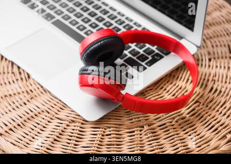 Red wireless headphones on laptop keyboard, modern technology for music and communication, digital lifestyle and entertainment Stock Photo