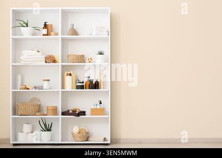 White bathroom shelf with personal care products and home decor items against a neutral wall Stock Photo