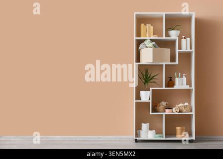 Modern white storage shelf with bathroom and home decor items against a warm peach wall, the shelf stands against a warm peach-colored wall, creating Stock Photo