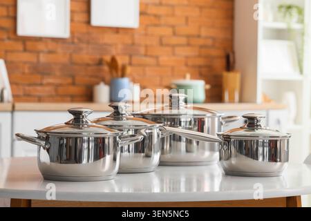 Stainless steel cookware set on kitchen table, modern home cooking utensils, culinary equipment for healthy meals Stock Photo