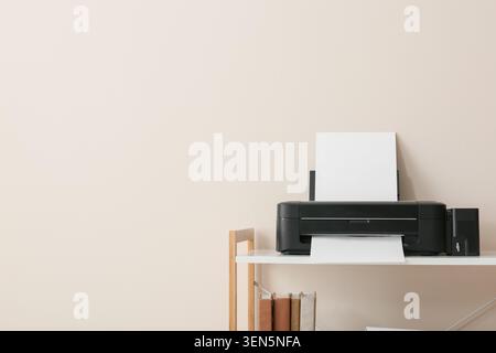 Modern black inkjet printer with blank paper on white shelf, home office technology and document printing Stock Photo
